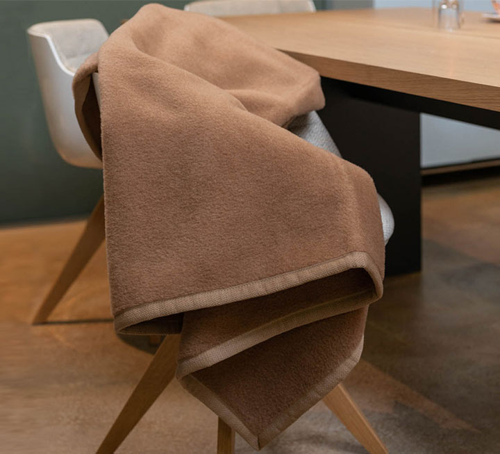 Kuscheldecke in hellem braun ausgebreitet über einem Stuhl Kuscheldecke in hellem braun ausgebreitet über einem Stuhl