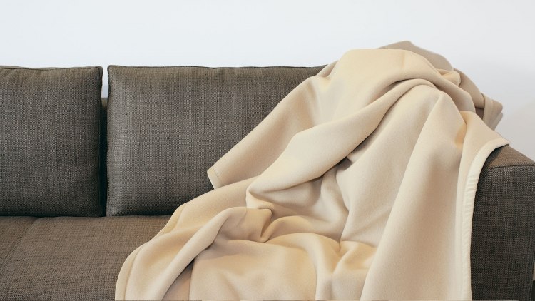 Heimdecke aus Cashmere und Merino-Lammwolle ausgebreitet auf einer Couch