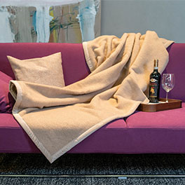 Wolldecke aus Kamelhaar in Farbe crème, ausgebreitet auf einem Sofa