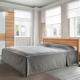 Tagesdecke in einem Schlafzimmer auf einem Bett ausgebreitet in der Farbe grau
