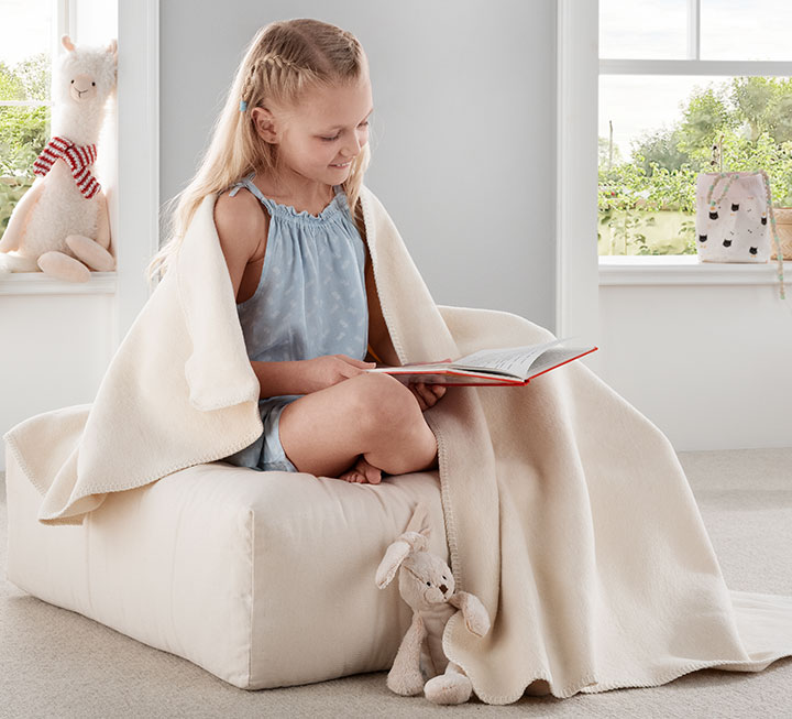 Plüschdecke in hellem Naturton ausgebreitet auf einem Sofa Plüschdecke in hellem Naturton ausgebreitet auf einem Sofa