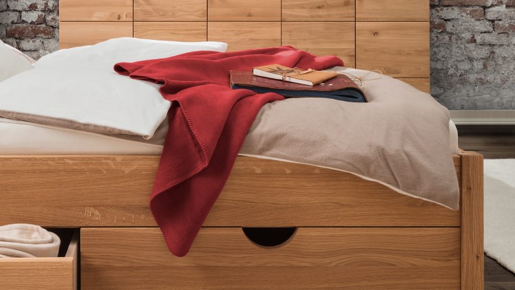 Gemütliche Baumwoll-Plüschdecke auf Bett - hier in rot